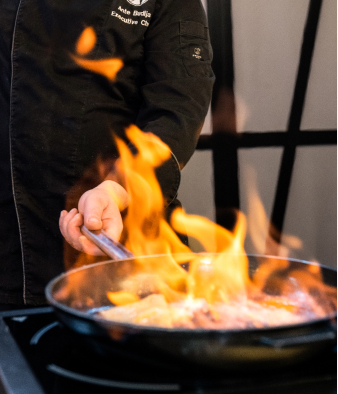 Catering Mitarbeiter beim Flambieren von Fleisch