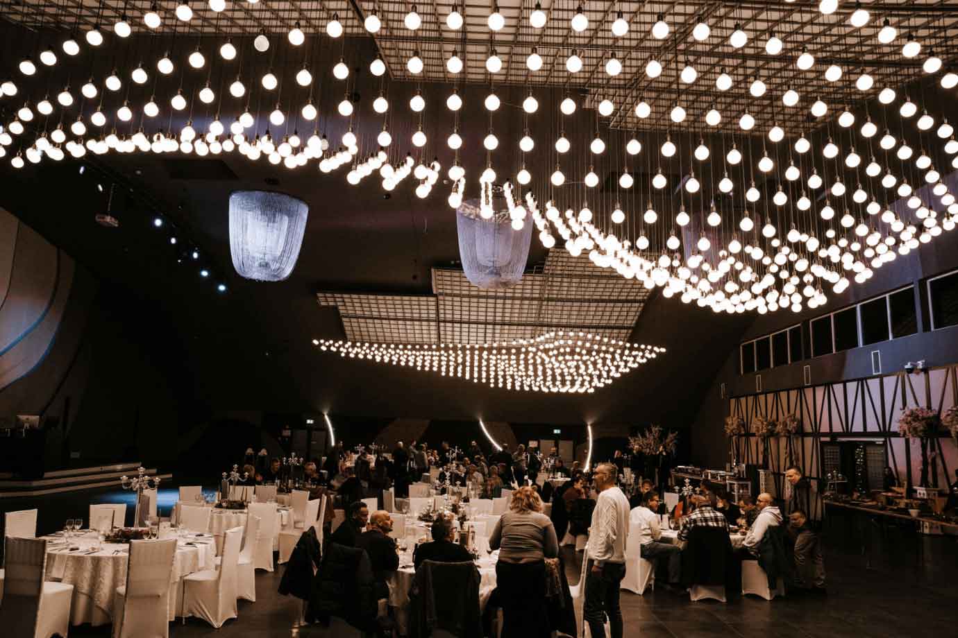 Gefüllter Eventsempfang mit elegant gedeckten weißen Tischen